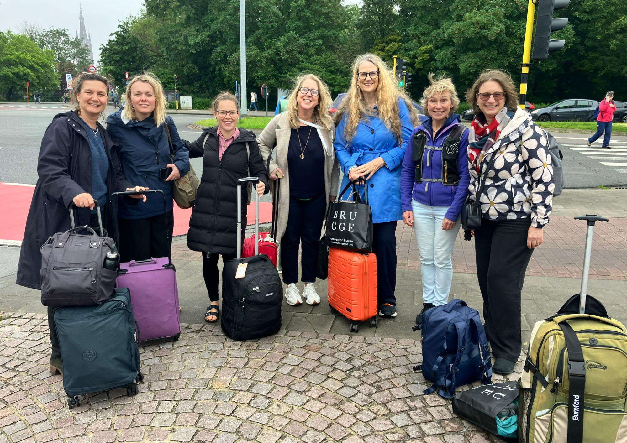 a group of therapists stood in a line with travel bags smiling at the camera