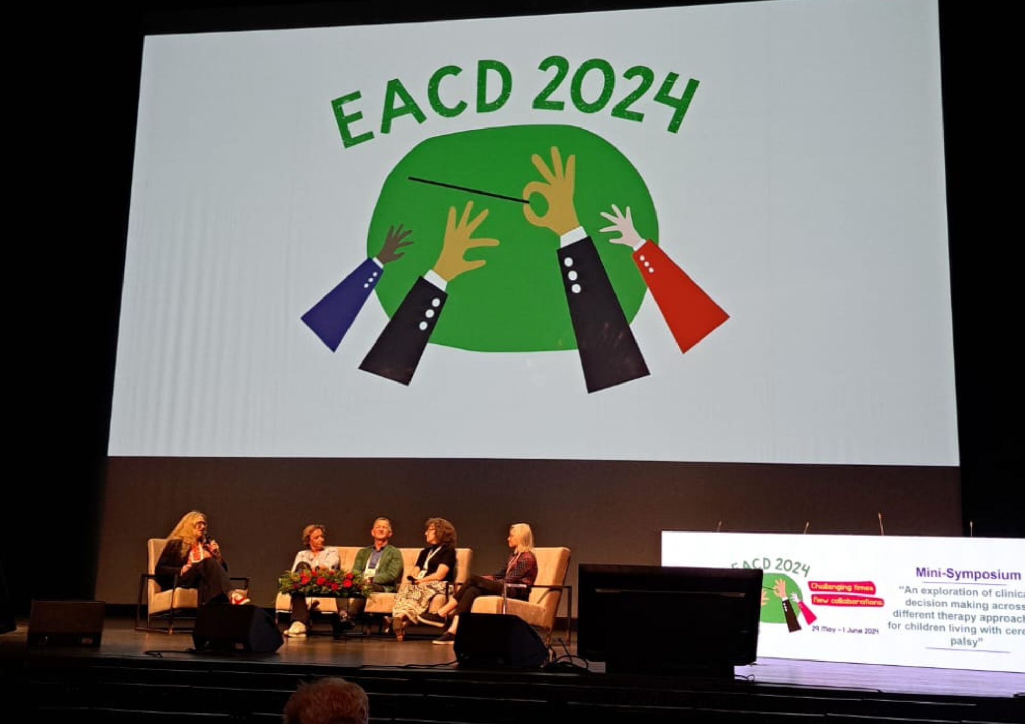 a group of clinical professionals sat on a stage in discussion