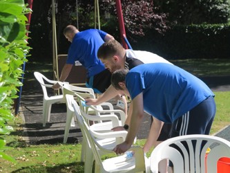 Group of men holding chairs.