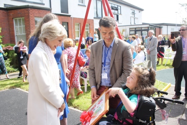 Duchess speaking with girl holding painting in wheelchair